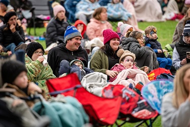 Crowd shot of a family wrapped in blankets watching a movie