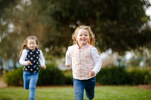 Two little girls running in park