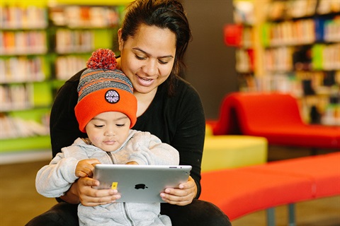 Mother and child reading iPad at library