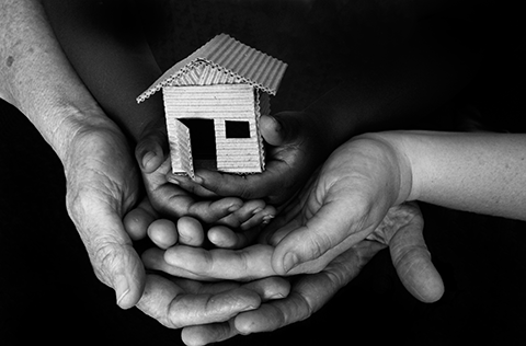 3 peoples hands holding a small model house