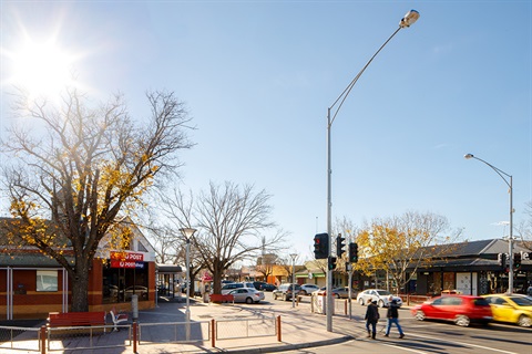 A view of cars and people moving around a shopping strip