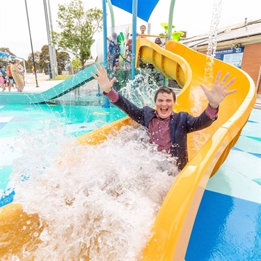 man in suit going down water slide at aqua park