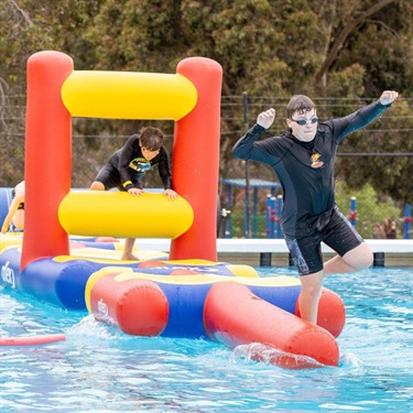child jumping off water park into pool