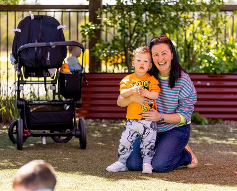 Parent and child playing in a park, smiling at camera