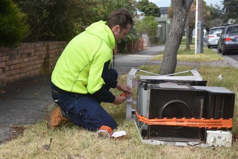 The Waste Response team member inspects evidence of dumped rubbish on a suburban nature strip