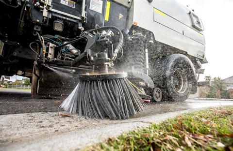 Close up of a street sweeper brush cleaning a road