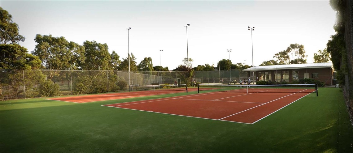 Wide shot of the Westmeadows Tennis Club featuring two of the courts and clubrooms