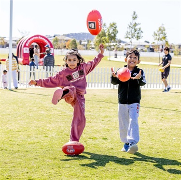 Two children kicking football on grass