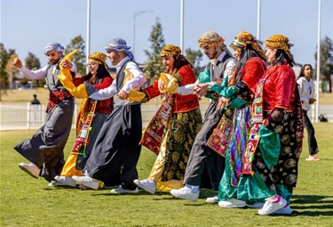 Group of dancers in cultural costume dancing on grass oval