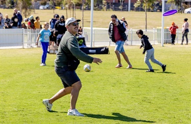 Community members playing soccer on a grass oval