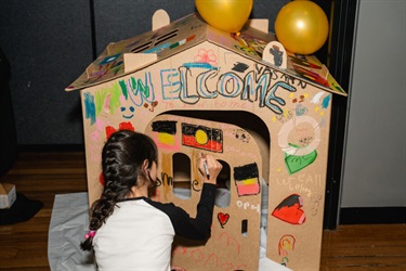 A child drawing on cardboard house 