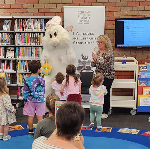 The Easter Bunny is singing and dancing along at a story time session in a library