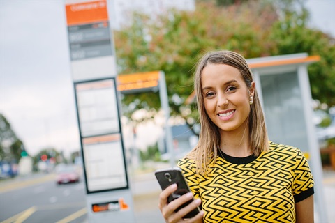 Woman at bus stop looks at mobile phone